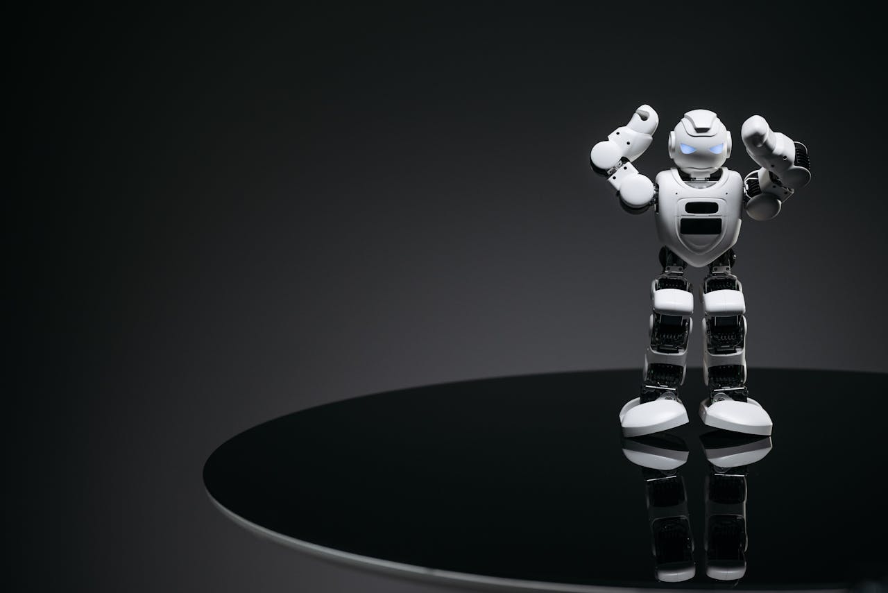 services-02 A small humanoid robot with glowing eyes on a reflective table in a dark setting.